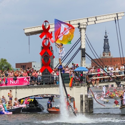 Pride Amsterdam canal parade with crowds and rainbow flags